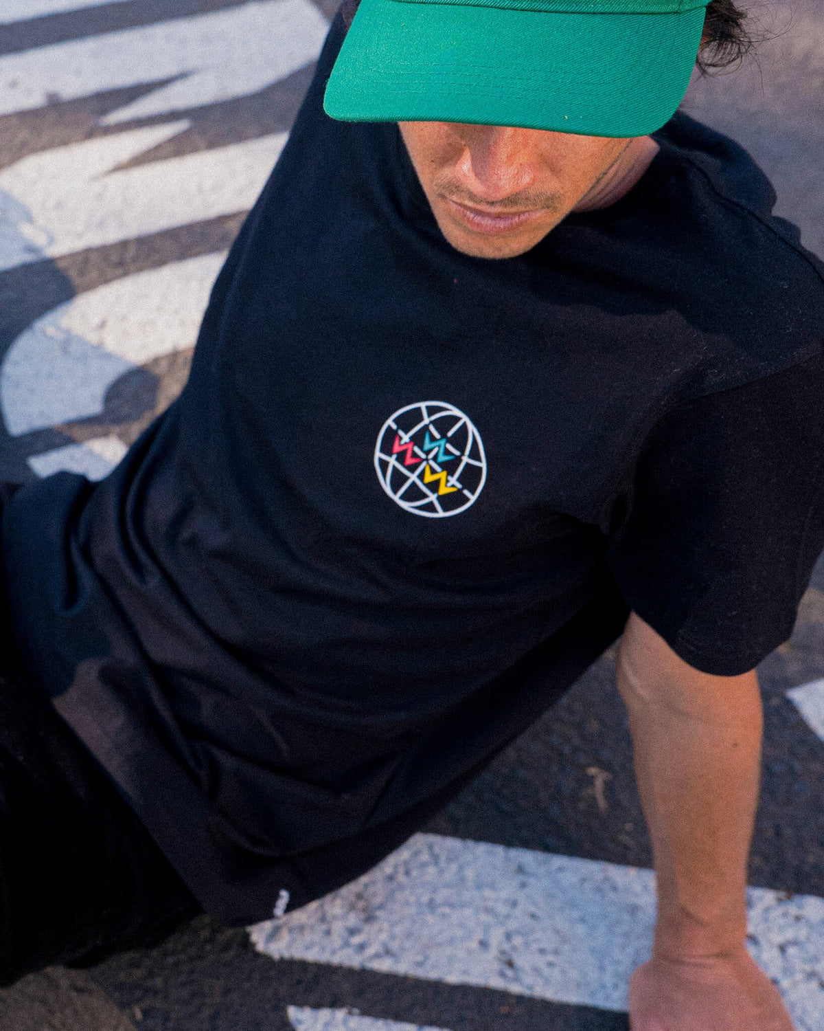 A man wearing a black crew neck t-shirt with a white globe graphic on the chest.