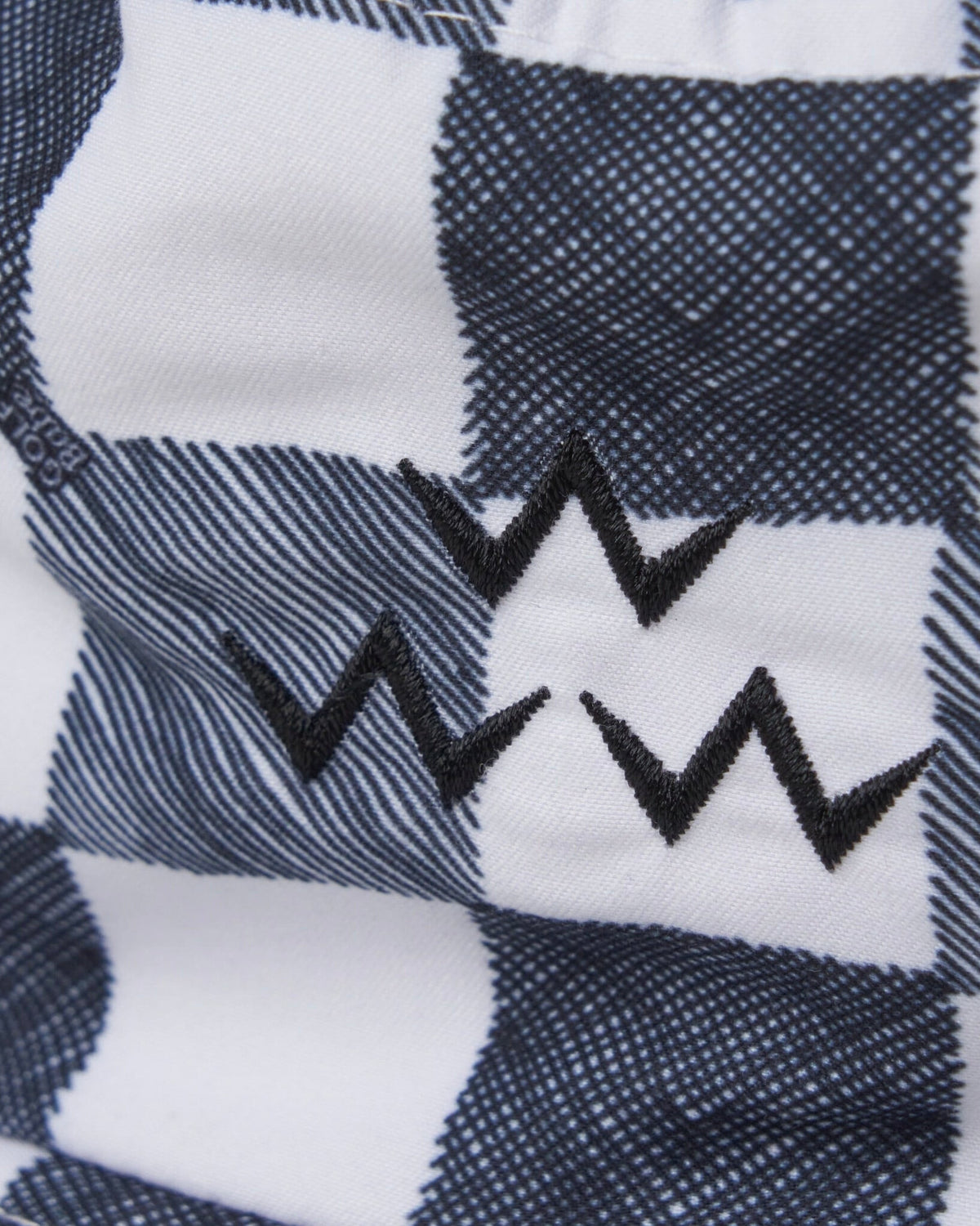 Detail of a black and white gingham bucket hat featuring a triple zigzag crown motif.