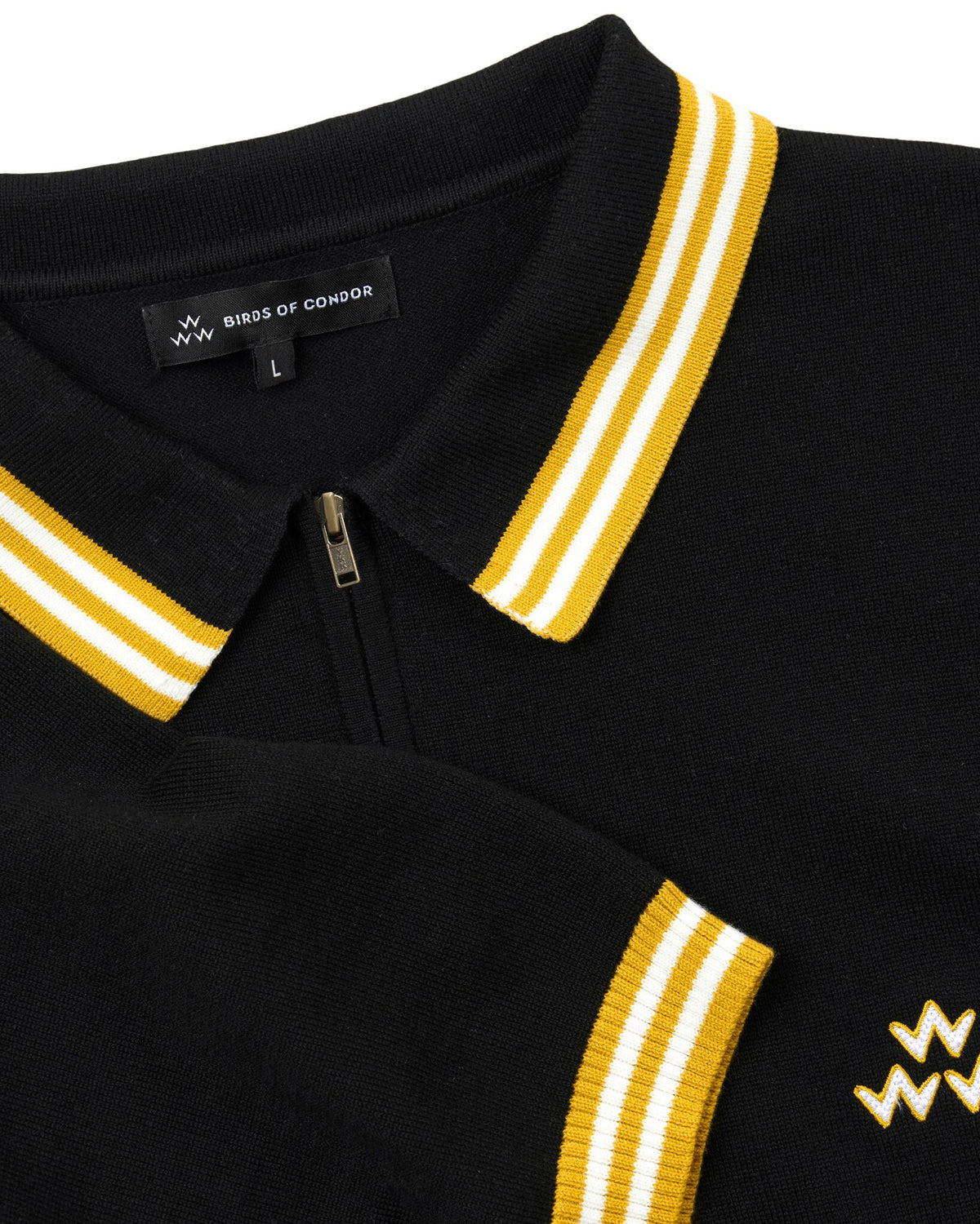 Detail of a black cotton knit polo with yellow and white striped collar trim, a quarter zip, and a triple eagle logo.