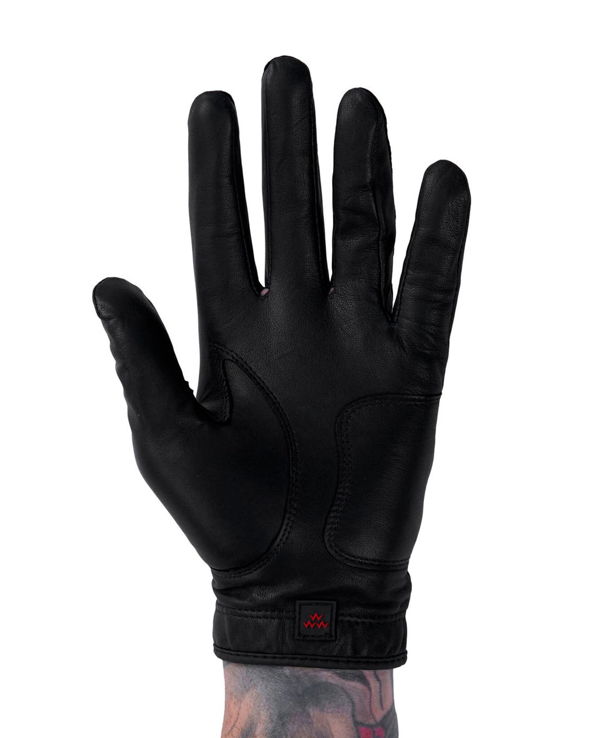 A black leather golf glove featuring a red triple eagle logo tag on the wrist band.