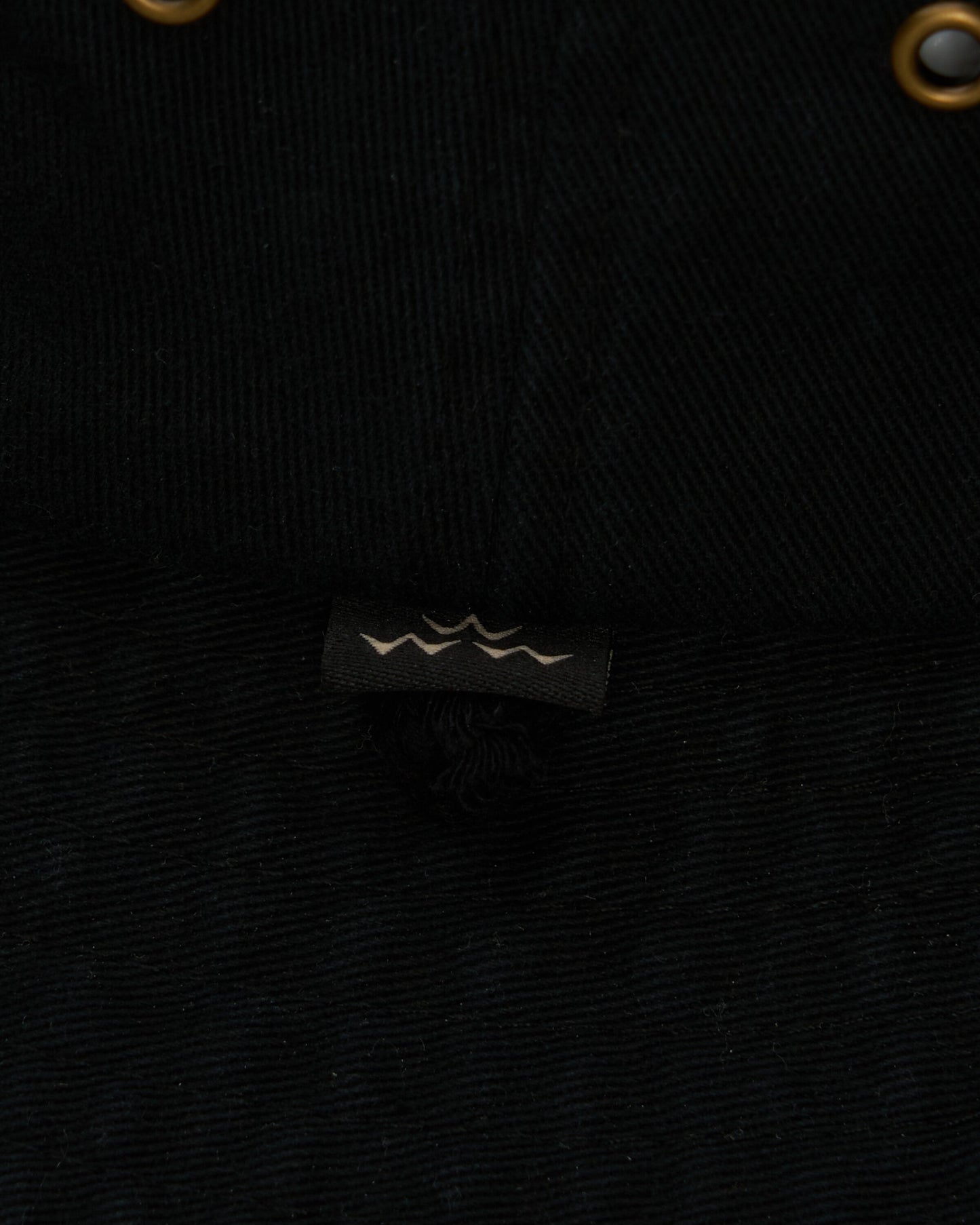 Detail of the black cotton canvas boonie hat with a small logo label.