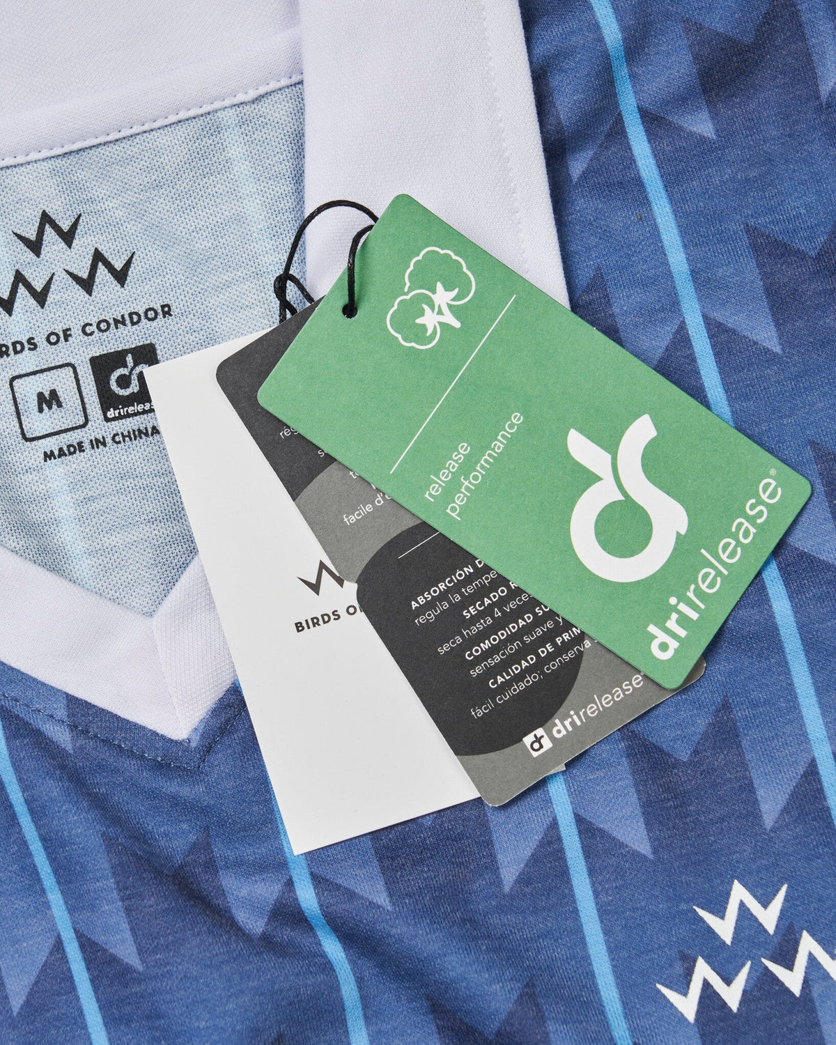 Detail of the navy and white football polo shirt, showing the V-neck collar, inner size print, and hanging tags.