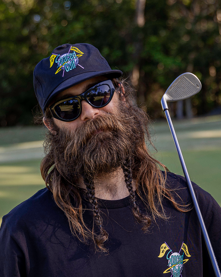 A man wearing a black soft peak cap with an embroidered Spaced Golf emblem.