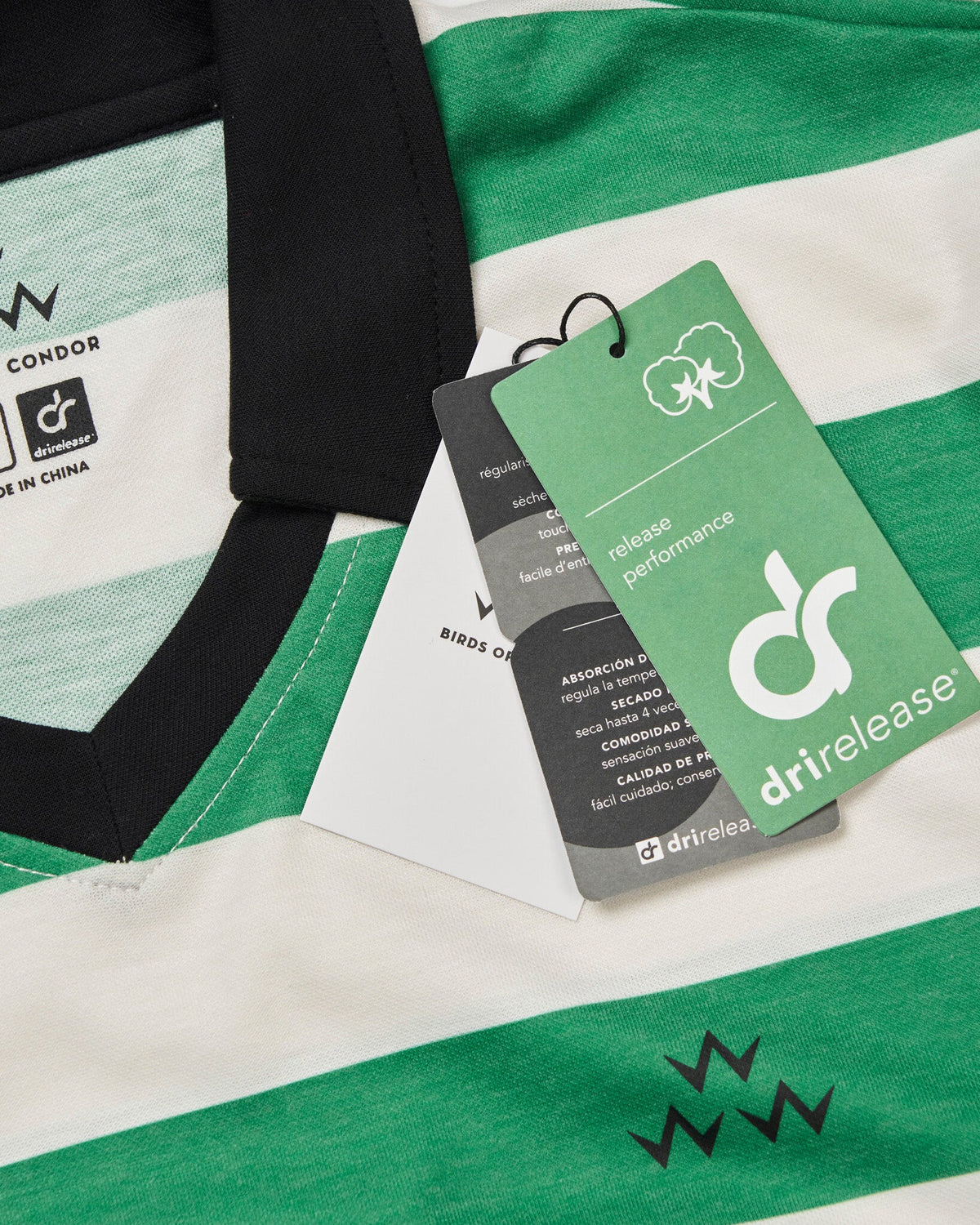 Detail of a green and white striped polo shirt with a black collar and hanging swing tags.