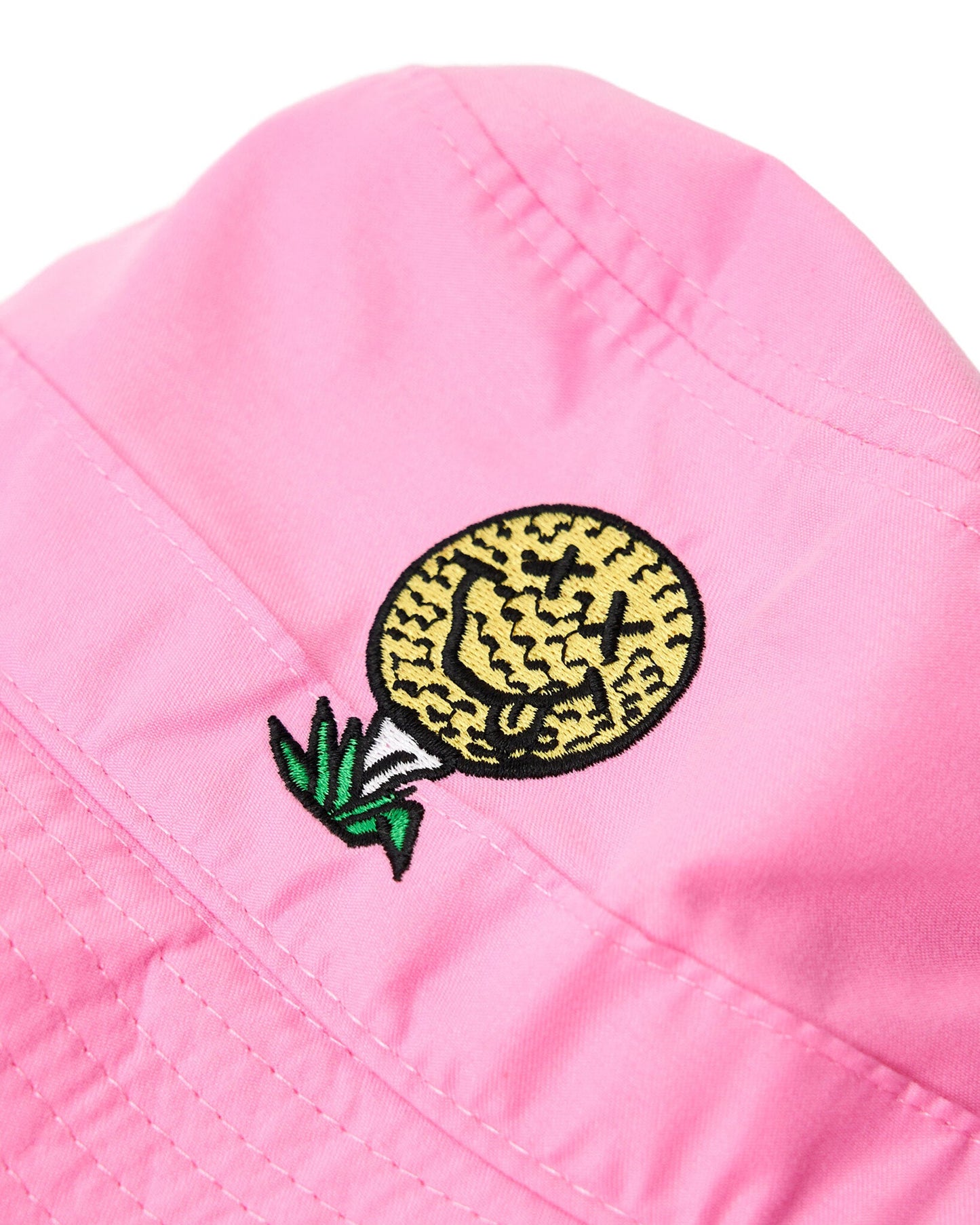 Detail of a pink bucket hat featuring an embroidered yellow smiley face golf ball on a tee motif.