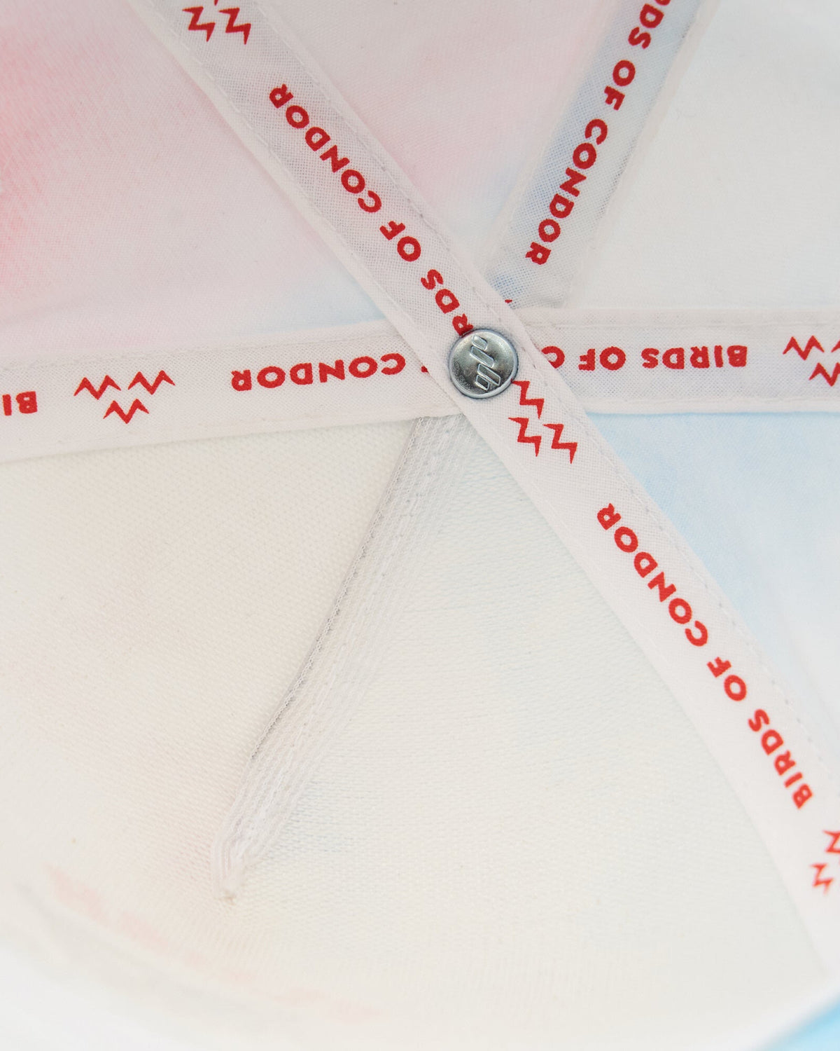 Detail of the interior lining of a tie dye cap, showing branded seam tape with text.