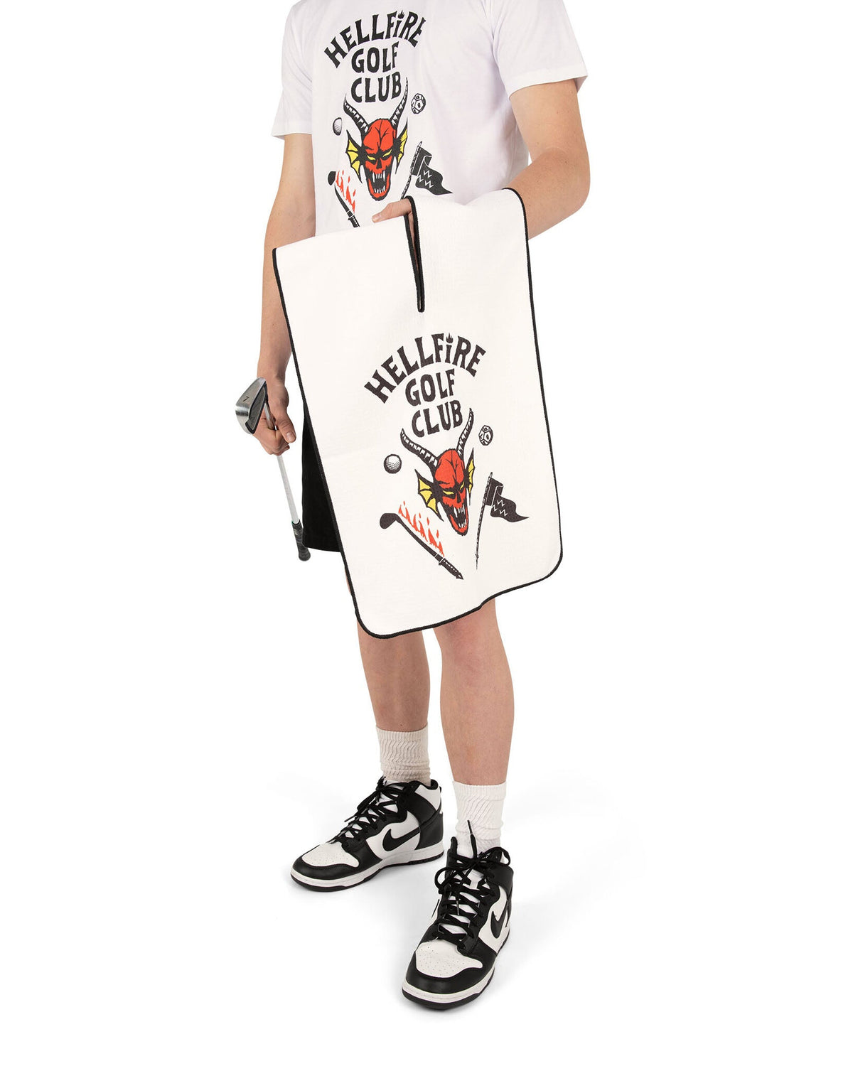 A person holding a white microfiber golf towel featuring a horned devil graphic and text.
