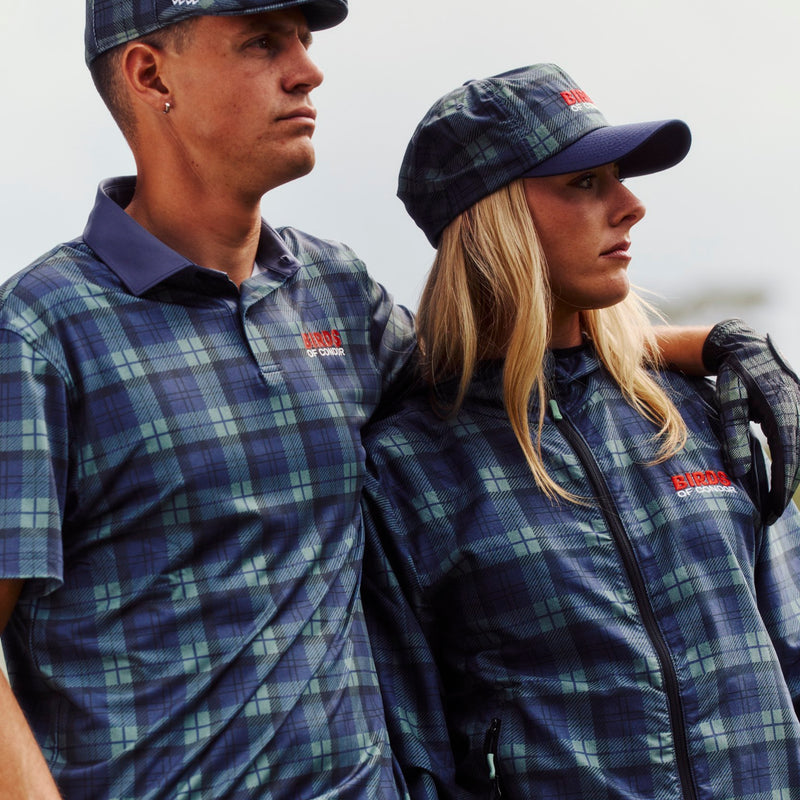 Two people wearing plaid clothing and caps against a white background