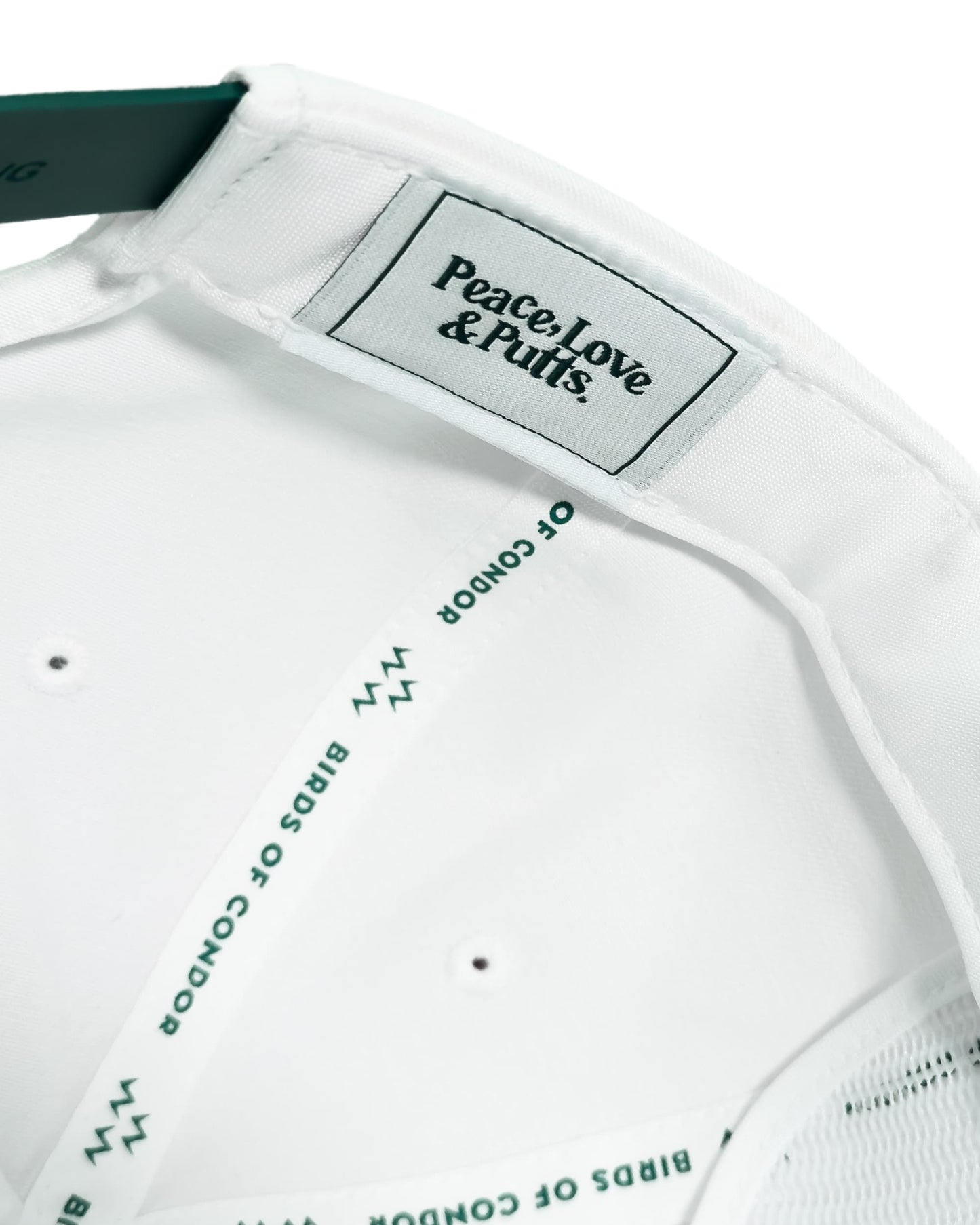 Close-up of a white shirt with 'Peace Love & Putts' label and text on a white background
