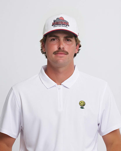 Man wearing a white polo shirt with a neverfind golf logo and a cap with 'Arizona Desert Golf Society' text on a plain background