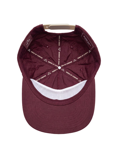 A top-down view of a maroon baseball cap with a white mesh band on the brim and white printed text on the interior panels.