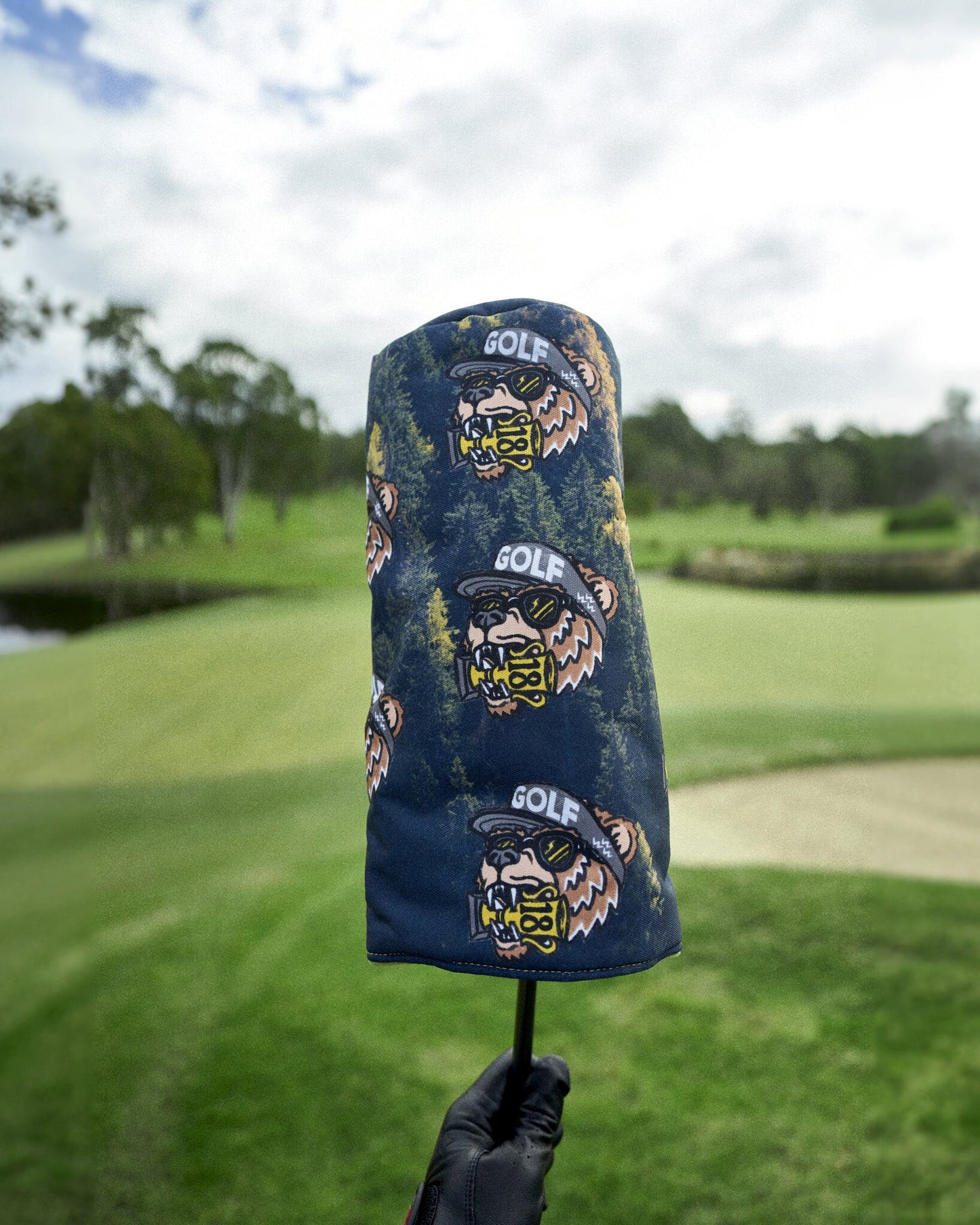Black headcover with an all-over forest print and a repeating bear graphic wearing sunglasses and a cap.