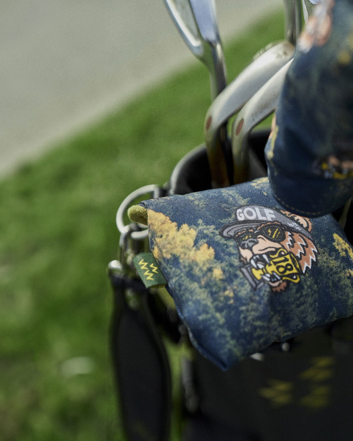 Black mallet putter headcover featuring a forest print and a bear wearing sunglasses graphic logo.