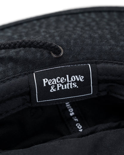 Detail of a black boonie hat featuring an inner woven label reading Peace, Love & Putts in white text.