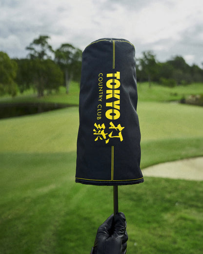 Black driver headcover featuring yellow vertical text and Japanese kanji graphics on a golf course.