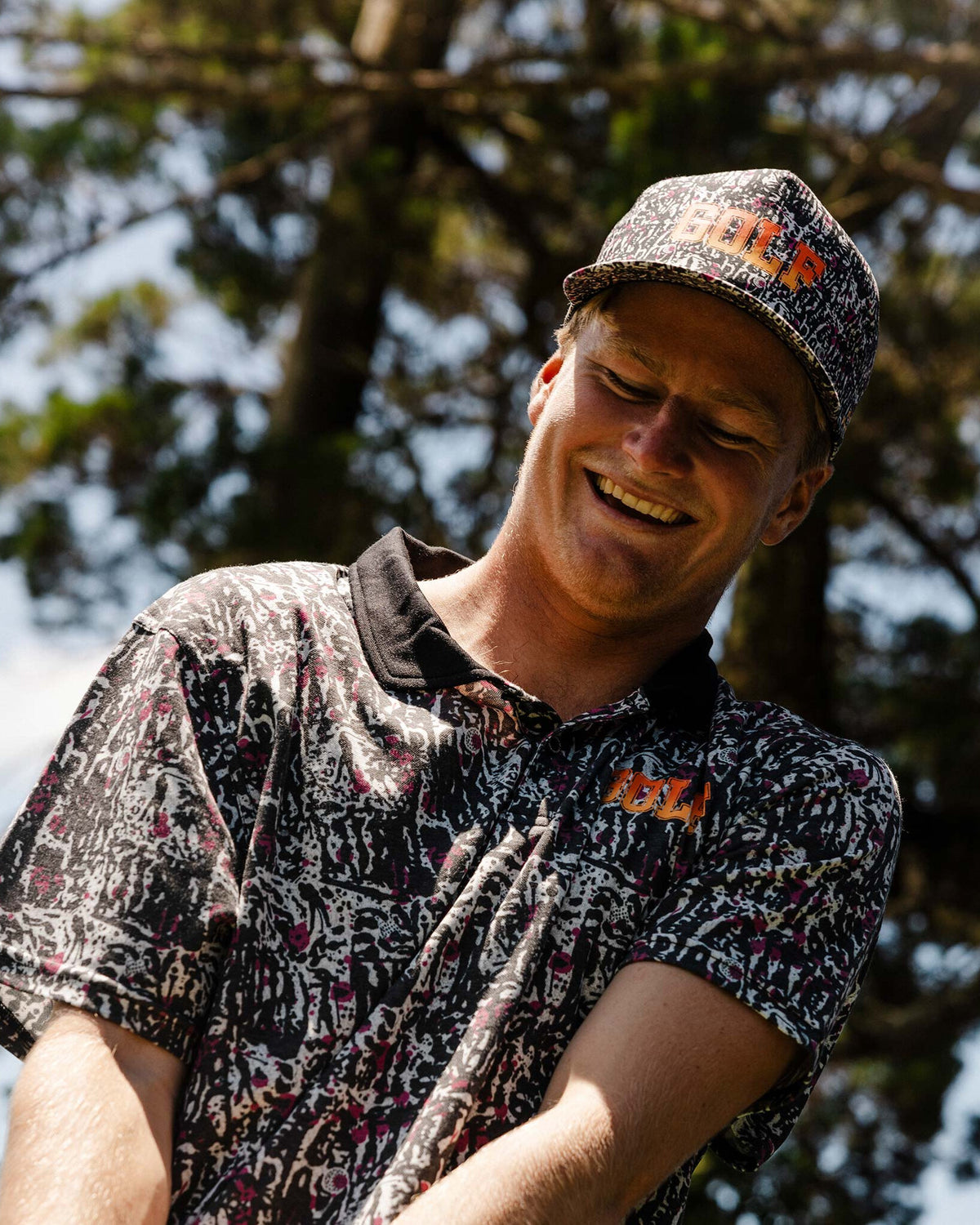 A smiling man wearing a black motley cap featuring a custom yardage print and a curved brim.