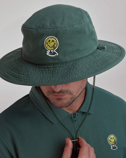 A man wearing a green boonie hat featuring a smiling golf ball logo and a matching green polo shirt.