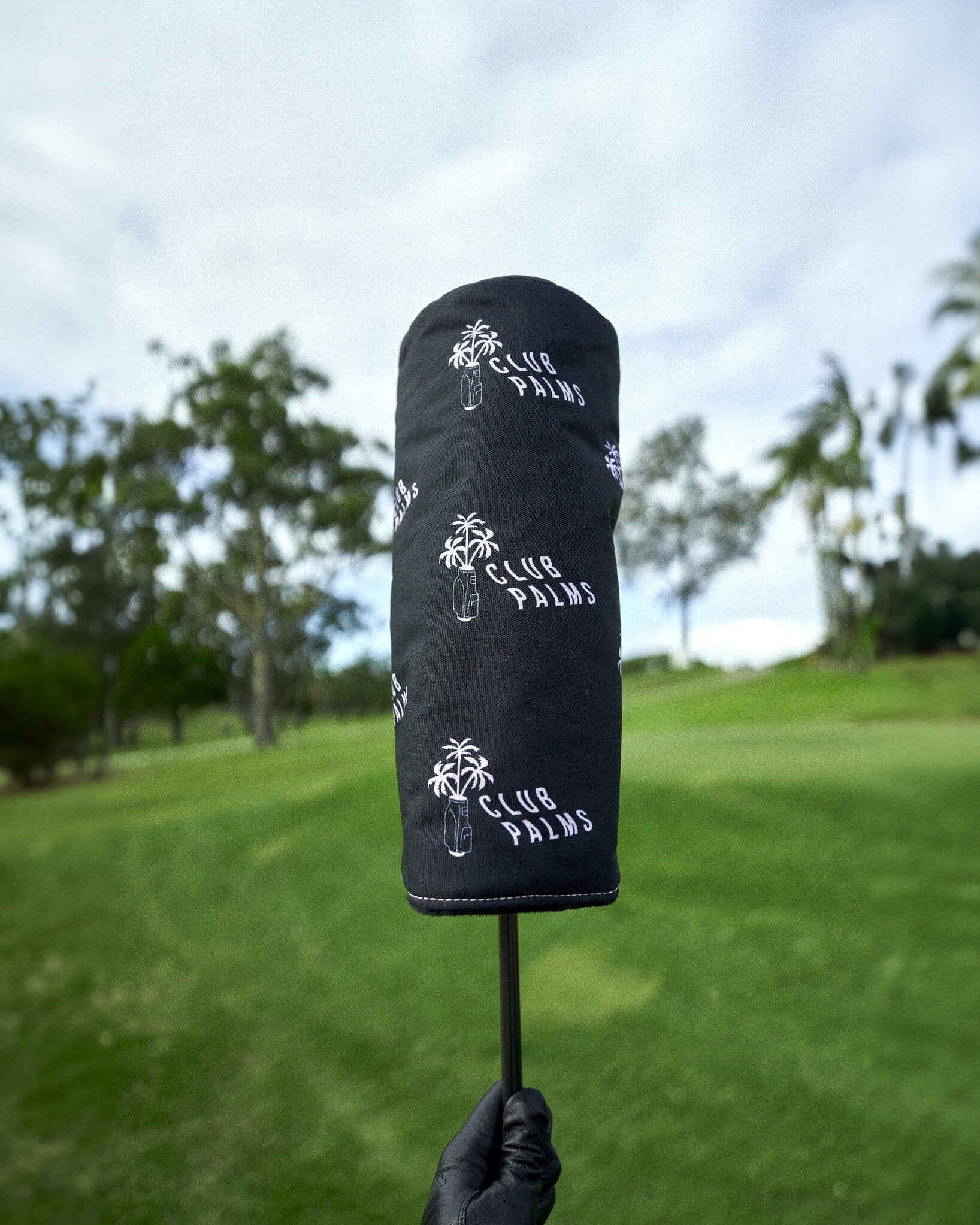 Black driver headcover featuring repeated white palm tree logos and Club Palms text.