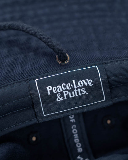 Detail of a navy boonie hat showing a woven label with white Peace, Love & Putts. text.