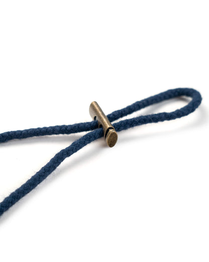 Detail of the navy boonie chin strap secured with a rectangular brass-toned metal toggle fastener.