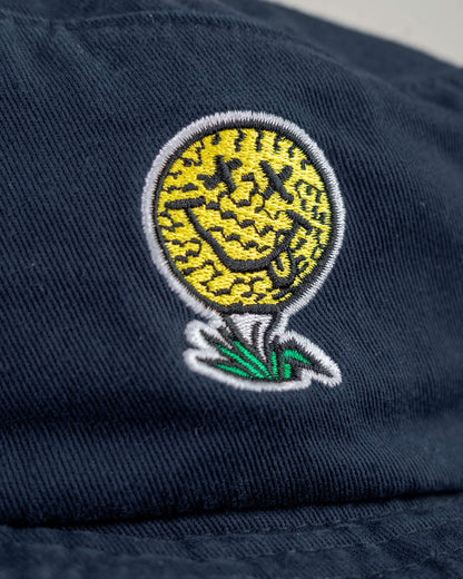 Detail of a navy cotton boonie featuring a yellow smiley face golf ball logo with X eyes on a white tee.