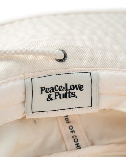 Detail of an off-white boonie hat showing a white interior brand label with text reading Peace, Love & Putts.