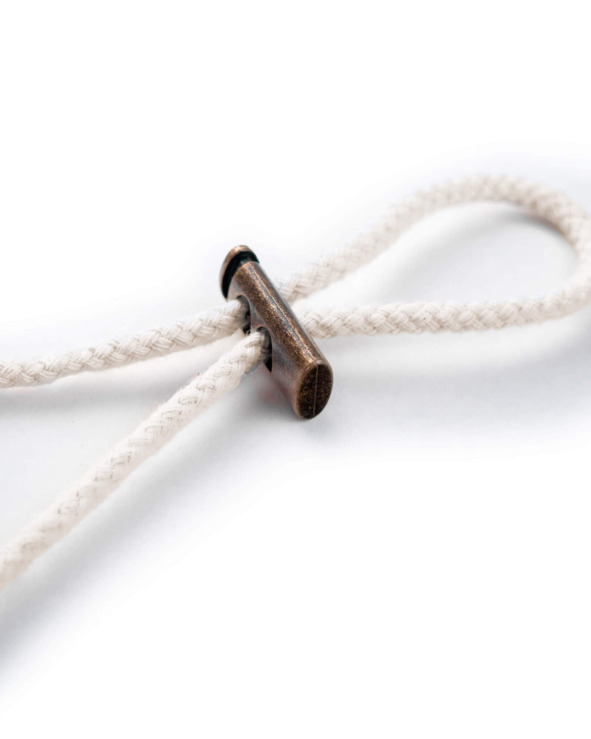 Detail of an off-white boonie hat drawstring secured with a dark metallic cylindrical toggle.