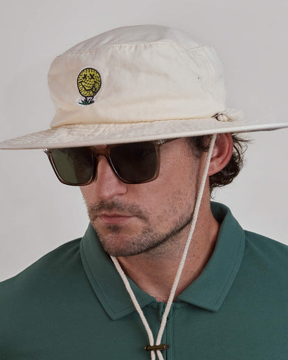 A man wearing an off-white cotton canvas boonie hat featuring a yellow smiley golf ball design.
