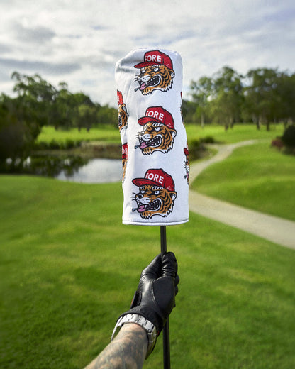 A gloved hand holding a white headcover with an all-over repeating angry tiger motif design.
