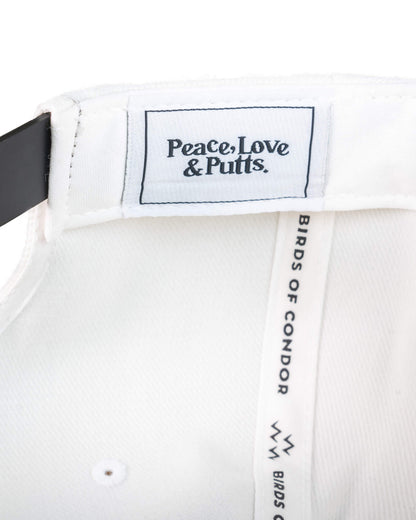 Detail of a white snapback's interior, showing a woven label reading Peace, Love & Putts.