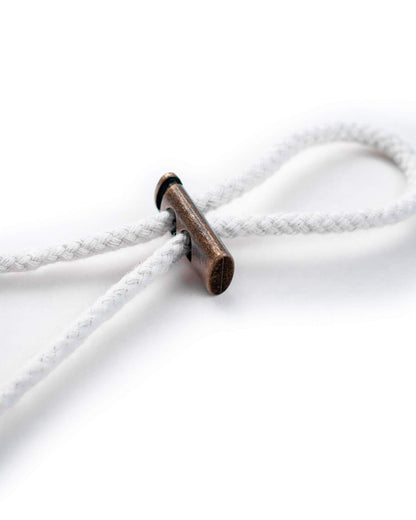 Detail of the white boonie chin strap featuring a metallic bronze toggle cinched on the cord.