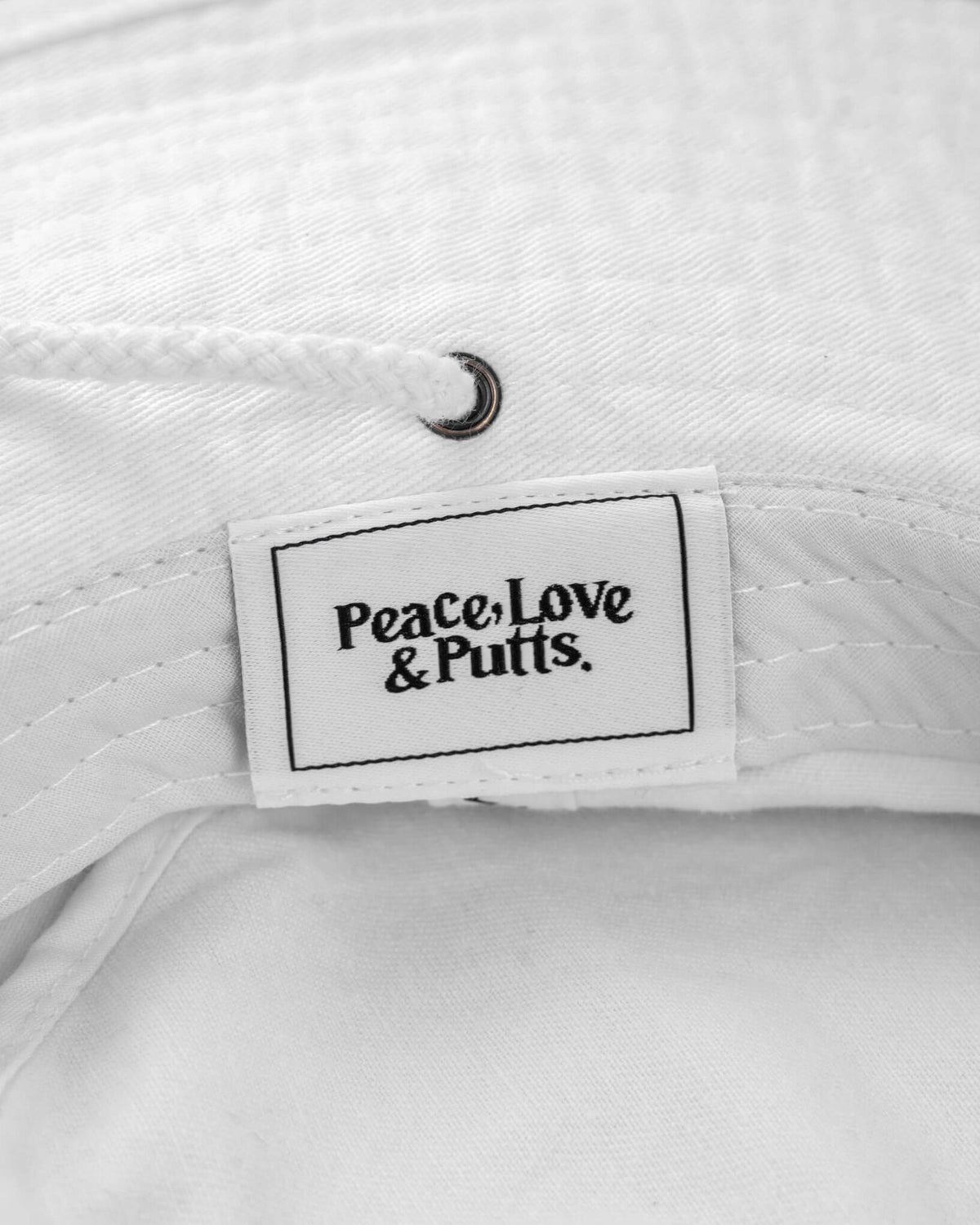 Detail of a white boonie hat with an interior woven label reading Peace, Love & Putts.