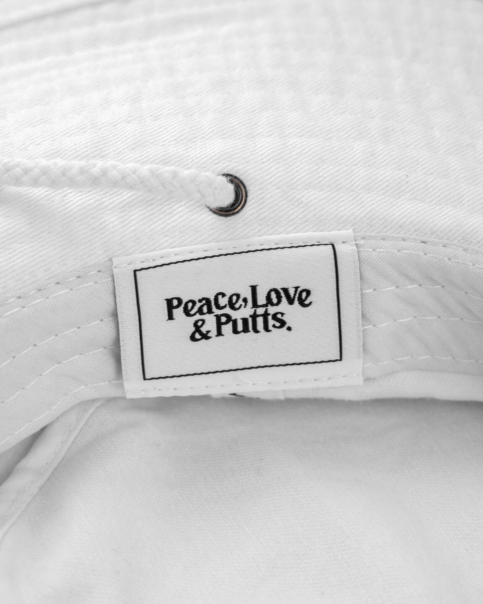 Detail of a white boonie hat with an interior woven label reading Peace, Love & Putts.