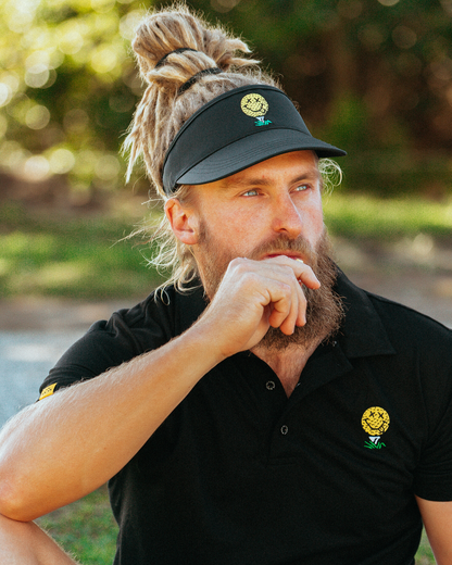 A man wearing a black visor featuring a yellow smiley face golf ball graphic on the front.
