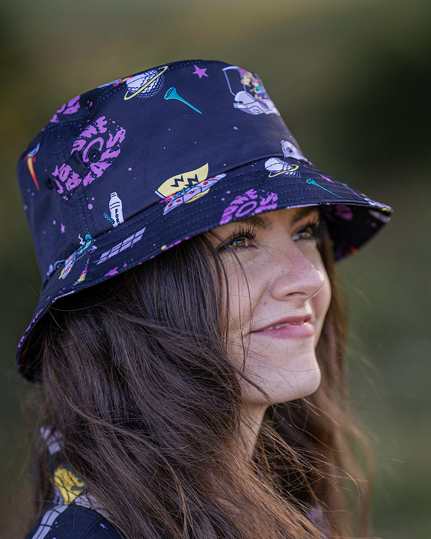 A woman wearing a black bucket hat featuring an all-over multicolored graphic galaxy print.