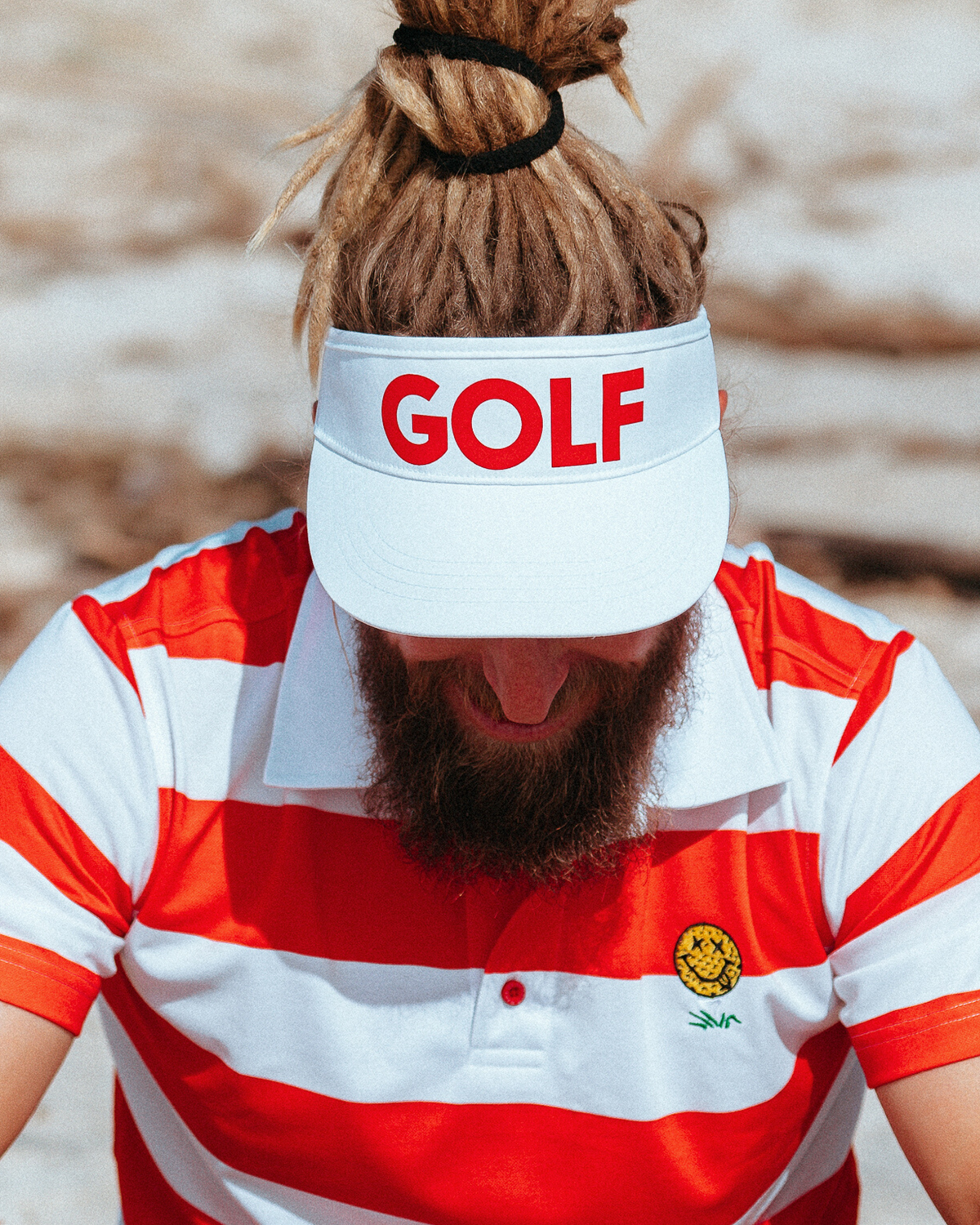 Person wearing a white golf visor featuring bold red GOLF text across the front panel.